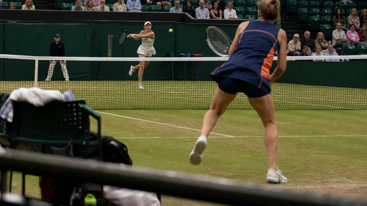 Två anonyma damspelare i en tennismatch på gräs.
